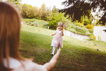 Happy little girl run to her mother for hugging in sunny day and smile, mothers day