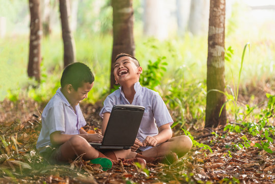 Smiling Asian boys using a laptop for education Choose focus on the eyes with a blurred background.