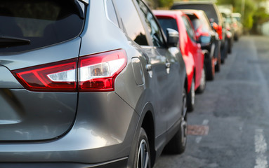 Closeup of rear, back side of blue car with  other cars parking in outdoor parking area beside the street in the evening. 