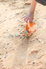 Girls are picking plastic waste on the beach. To help maintain a good environment.