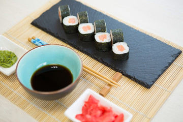 Plate of tempura maki sushi rolls with cream cheese, avocado and tuna at decorated with flowers table background. Healthy and tasty food.