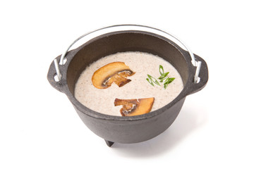 Mushroom soup in brutal rustic black metal pot on white Healthy and tasty food.