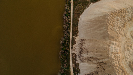 A road between a quarry and a field, shot from above.