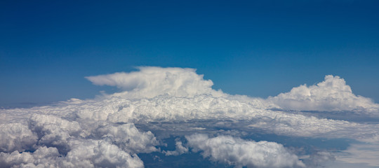 Blue sky and fluffy clouds. View out of a plane window.
