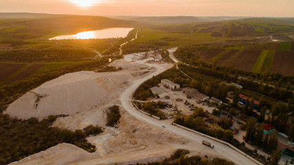 A village next to a quarry and a forest at sunrise.