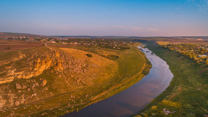 A cliff next to a river, at sunrise, shot from above.