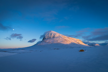 Fototapeta na wymiar A tent in the mountains of Sarek National Park, Lapland, during a winter sunset. 