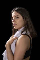 Naklejka premium Moody portrait of a sporty young girl with a towel around her neck on a black background.