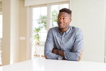 Fototapeta premium Handsome african american man on white table smiling looking side and staring away thinking.