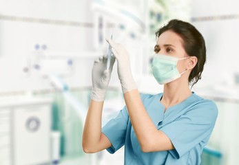 Attractive young female doctor with syringe on blurred hospital interior on background