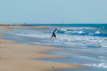 fisherman casting a line from a beach