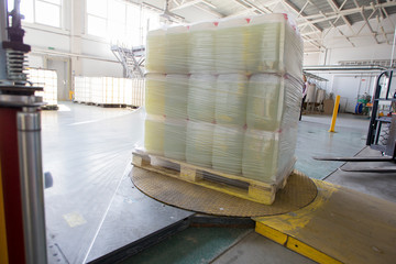 The machine for packing cellophane. Plastic jars wrapped in cellophane