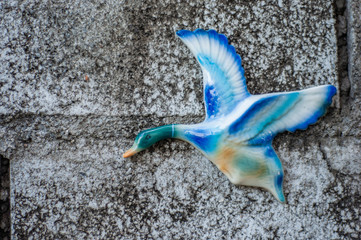 Ceramic flying duck blue and white on the concrete wall.