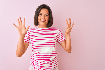 Young beautiful woman wearing striped t-shirt standing over isolated pink background showing and...