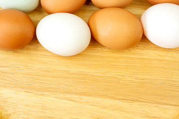 White and brown eggs on wooden background.