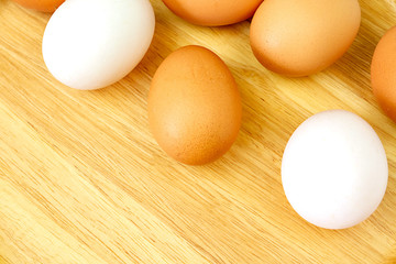 White and brown eggs on wooden background.
