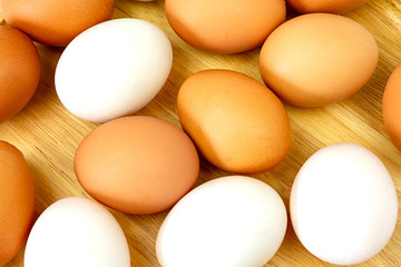 White and brown eggs on wooden background.