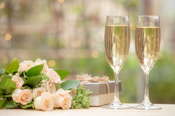 Rose flower, gift box, glass wine, on wooden table with bokeh background