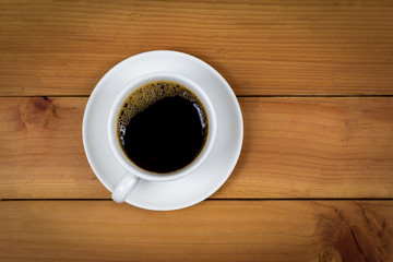Cup of coffee on wood background, top view.
