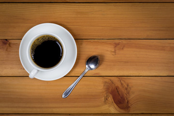 Cup of coffee on wood background, top view.