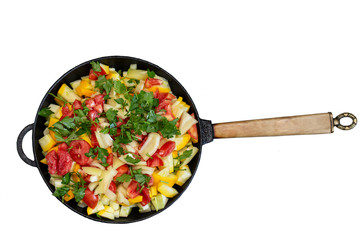 Frying pan with vegetables on a white background. Fried tomatoes, zucchini and herbs
