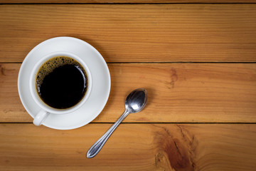 Cup of coffee on wood background, top view.
