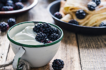 Morning meal, yogurt, fresh summer blackberries in rural mug