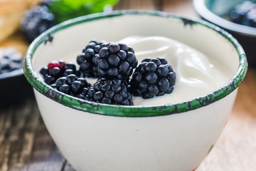 Morning meal, yogurt, fresh summer blackberries in rural mug