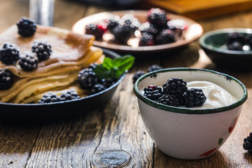 Crepes,yogurt in rural mug, fresh blackberries, healthy breakfast