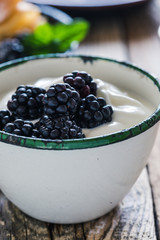 Morning meal, yogurt, fresh summer blackberries in rural mug