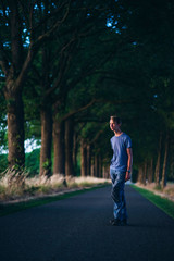 Young man on country road at sunset.