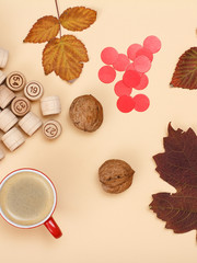 Wooden lotto barrels, dry leaves, walnuts and cup of coffee on beige background. Autumn theme.