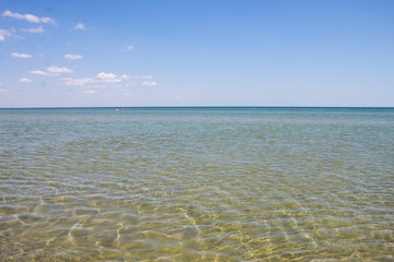 Summer beautiful seascape - transparent sea with a sandy bottom and blue sky, summer breeze.