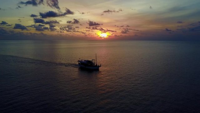 Aerial Circling: Fishing Boat Moving on the Ocean in Beautiful Sunset, Uluwatu, Bali, Indonesia