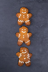 Christmas cookies - gingerbread man, white glaze on gray concrete background. Recipe, invitation concept. Top view, flat lay, close-up, copy space, vertical layout design