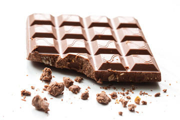 Broken piece of chocolate with crumbs on a white background. Cocoa Dessert