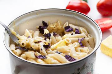 Macaroni in a pan with cheese and herbs close-up