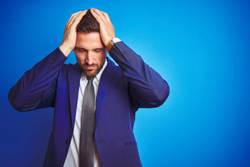 Young handsome business man over blue isolated background suffering from headache desperate and...