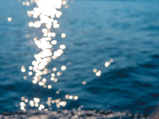 Sun glare on the waves in the sea. Blurred background, out of focus.