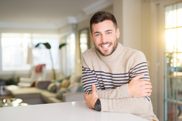 Fototapeta premium Young handsome man at home happy face smiling with crossed arms looking at the camera. Positive person.