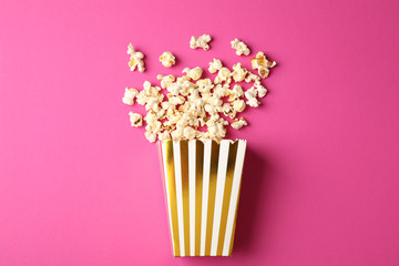 Flat lay composition with striped box and popcorn on color background