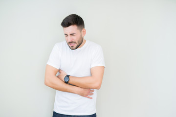 Young handsome man wearing casual white t-shirt over isolated background with hand on stomach because nausea, painful disease feeling unwell. Ache concept.