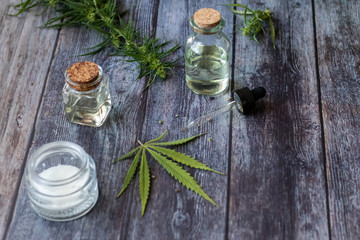 Cannabis hemp creams with marijuana leaf on wooden background - topical cannabis oil concept
