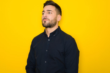 Obraz premium Young handsome man possing and modeling over yellow isolated background