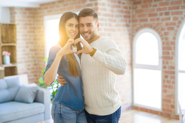 Young couple moving to a new home, hugging in love showing keys of new apartment smiling very happy