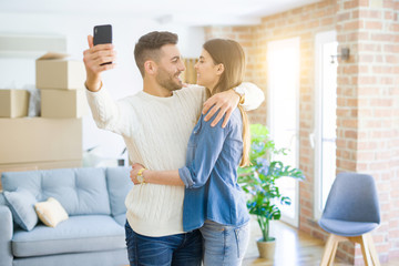 Fototapeta premium Beautiful couple taking a selfie photo using smartphone at new apartment, smiling happy for new house
