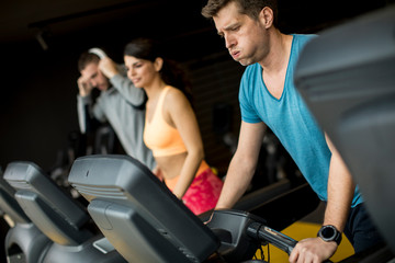 Fototapeta premium Young people using threadmill in modern gym