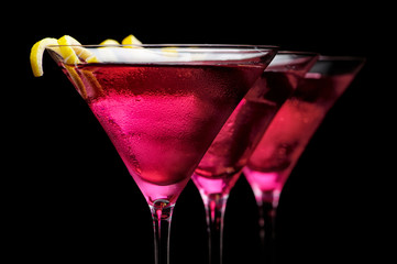  Cropped three cosmopolitan cocktails in line on black background