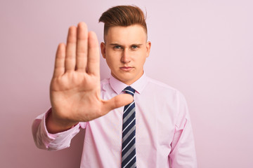 Young handsome businessman wearing shirt and tie standing over isolated pink background doing stop...