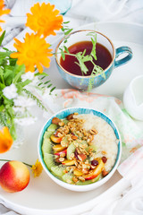 Bowl of fresh oatmeal porridge with kiwi, peach and granola